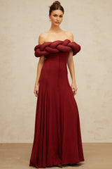 Woman wearing a long red knit maxi dress with braided design details
