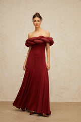 Woman wearing a long red knit maxi dress with braided design details