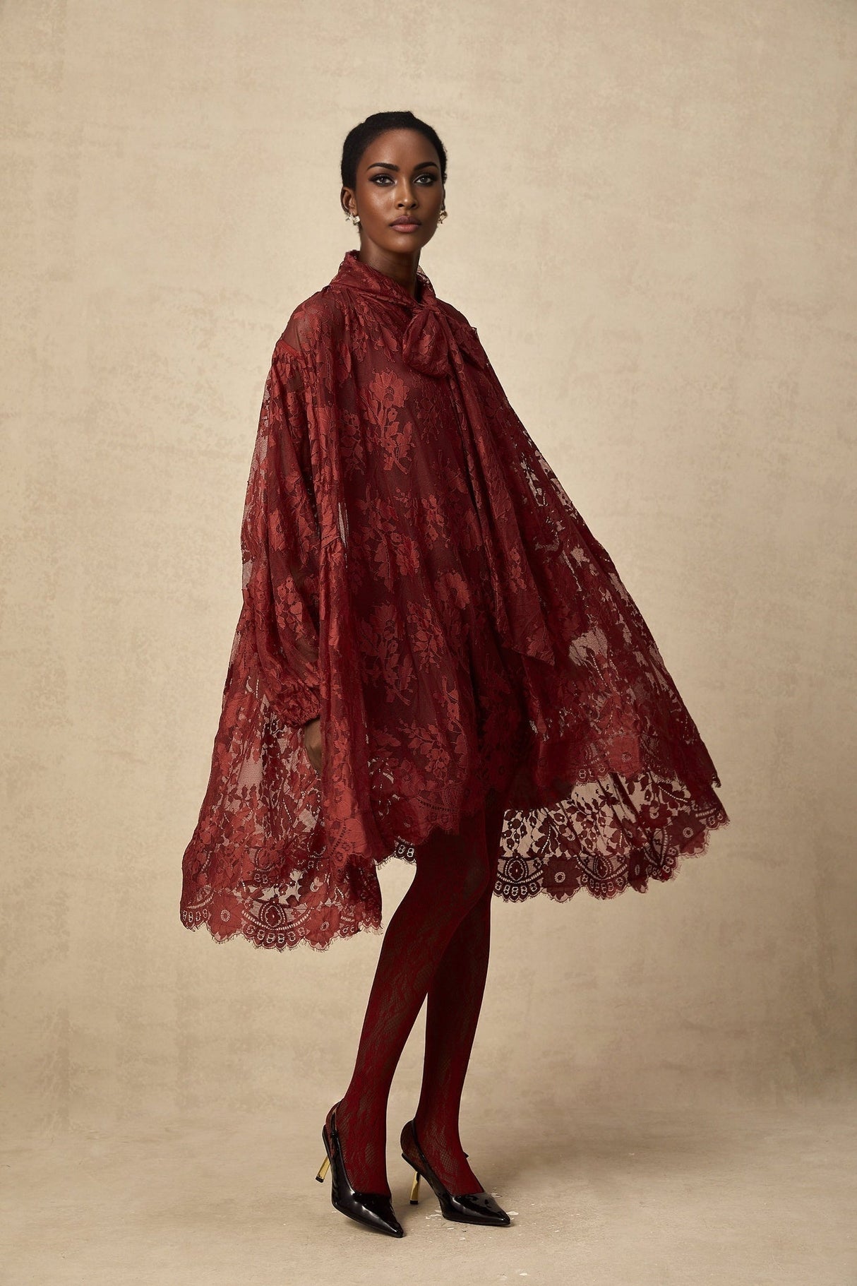 Woman wearing a long red lace dress with loose fit and sheer details
