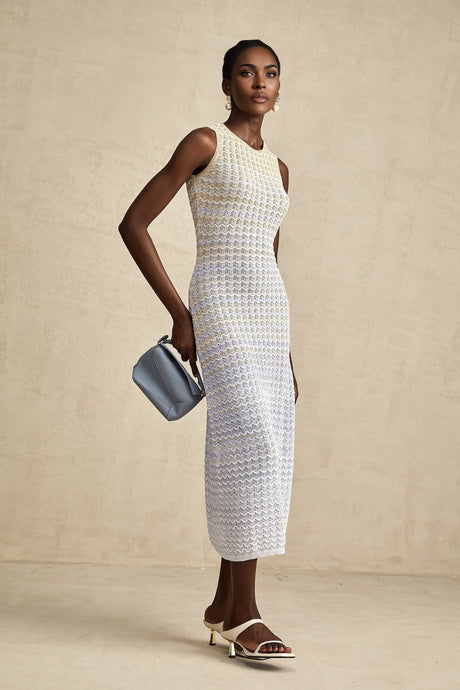 Woman wearing a long ribbed knit dress with contrasting color details and a midi length silhouette