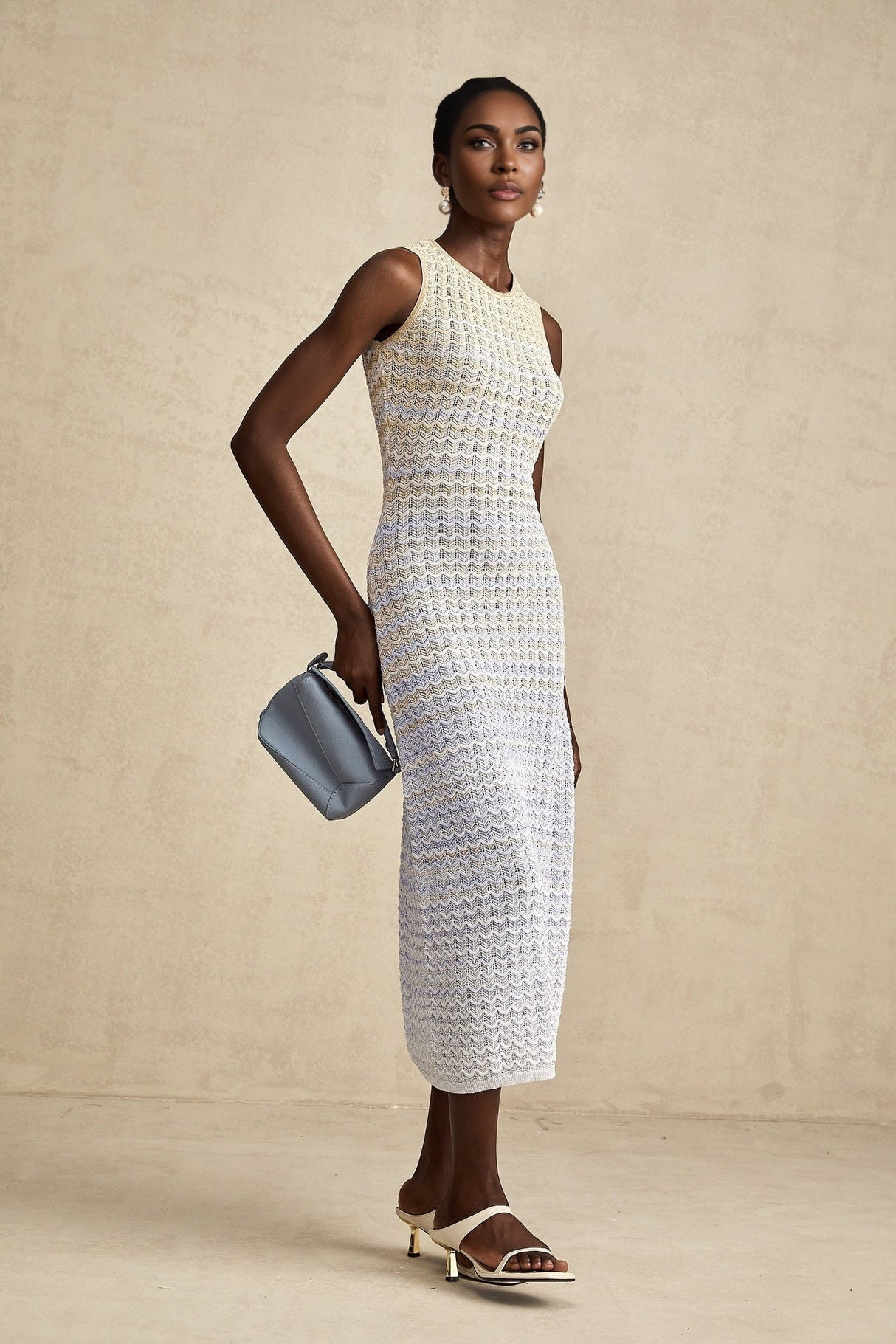 Woman wearing a long ribbed knit dress with contrasting color details and midi length
