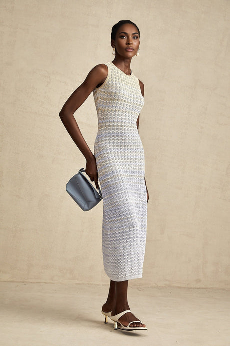 Woman wearing a long ribbed knit dress with contrasting color details and midi length