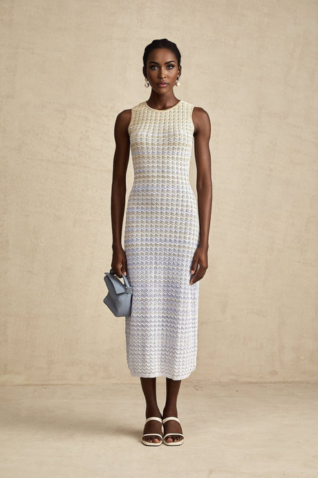 Woman wearing a long ribbed knit dress with contrasting color details and midi length