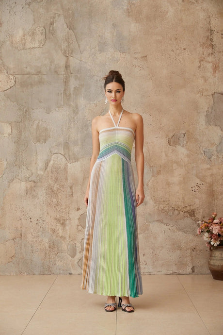 Woman wearing a long shimmering metallic knit dress with open back standing in elegant pose