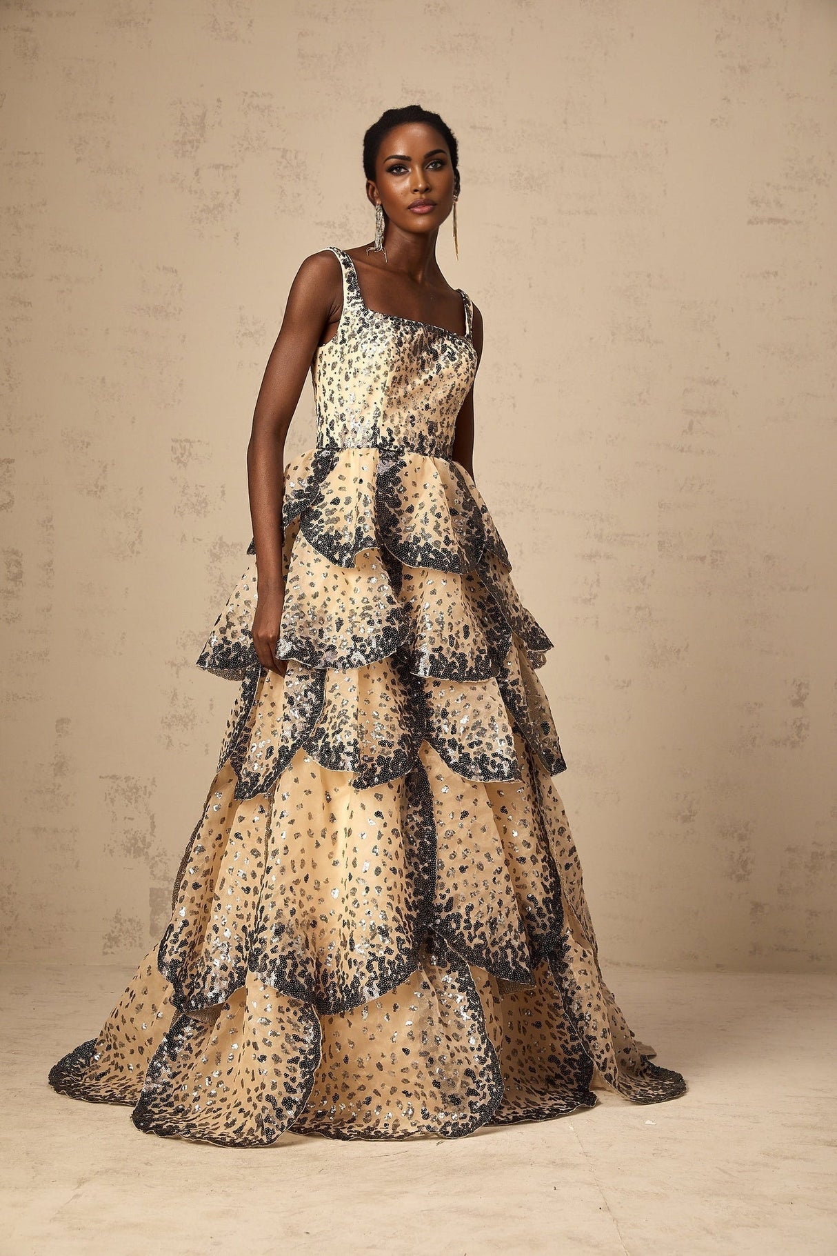 Woman wearing a long tiered maxi dress with sequined petal details and a flowing silhouette