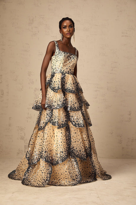 Woman wearing a long tiered maxi dress with sequined petal details and a flowing silhouette