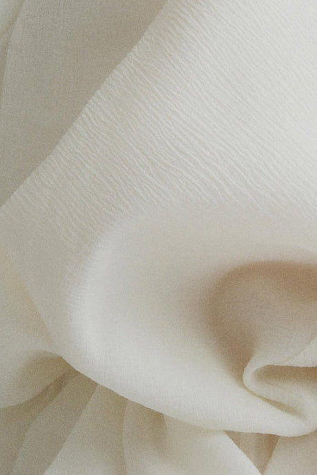 Woman wearing a long white maxi dress with ruffled details and a tie neckline