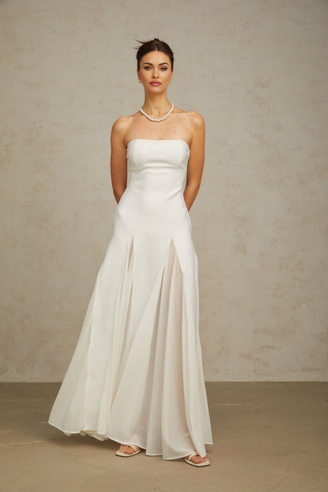 Woman wearing a long white maxi dress with tulle panels flowing elegantly to the floor