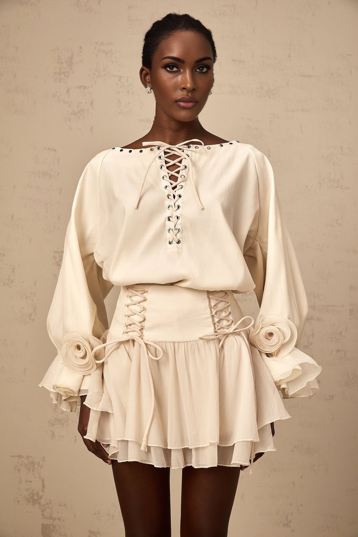 Woman wearing a matching blouse and skirt set in light fabric The blouse has ruffles and a self tie detail The skirt is flowy and coordinated with the top