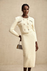 Woman wearing a matching knit cardigan and skirt set with embellishments named Justine The outfit features decorative details and a coordinated design