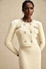 Woman wearing a matching knit cardigan and skirt set with embellishments named Justine The outfit features decorative details on a coordinated knitwear ensemble