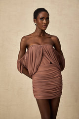 Woman wearing a matching offshoulder bodysuit and skirt set in a solid color fabric