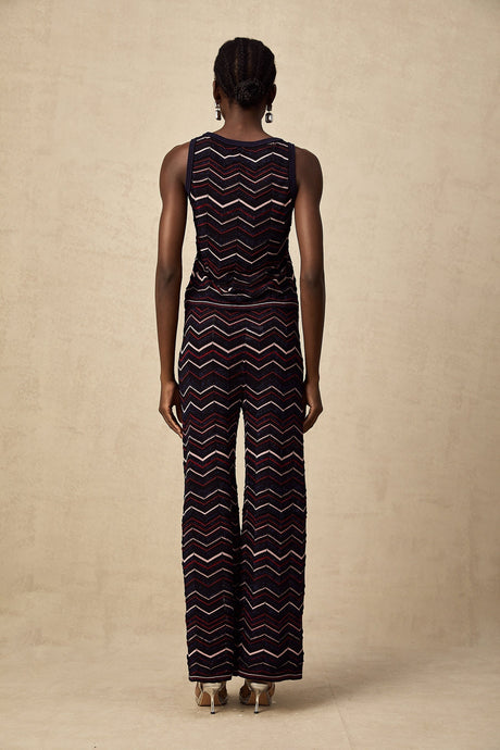 Woman wearing a matching set consisting of a crochet knit top and trousers with a zigzag pattern in a bohemian style