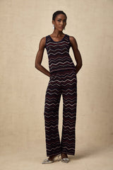Woman wearing a matching set consisting of a crochet knit top and trousers with a zigzag pattern in a light color