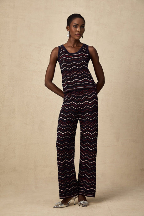 Woman wearing a matching set consisting of a crochet knit top and trousers with a zigzag pattern in a light color
