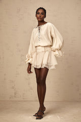 Woman wearing a matching set consisting of a ruffled blouse with selftie details and a coordinating skirt in a light fabric