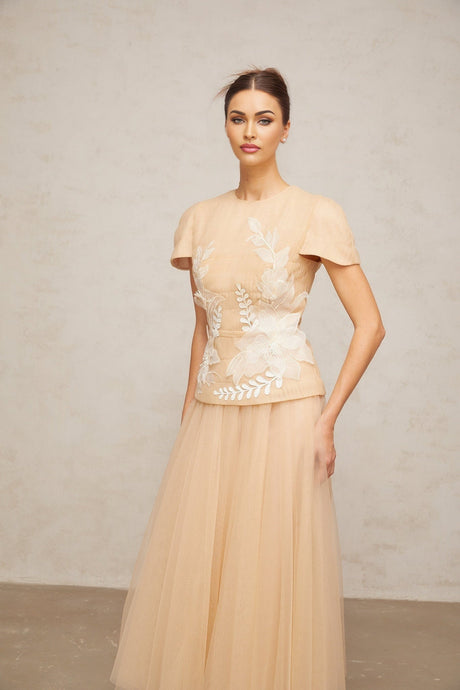 Woman wearing a matching set consisting of a sheer tulle top and skirt adorned with floral appliques in a delicate and romantic style