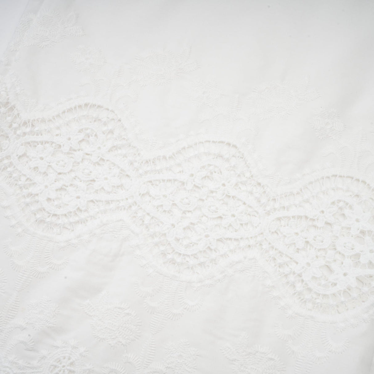Woman wearing a matching set of white lace trim cropped top and trousers with cutout details
