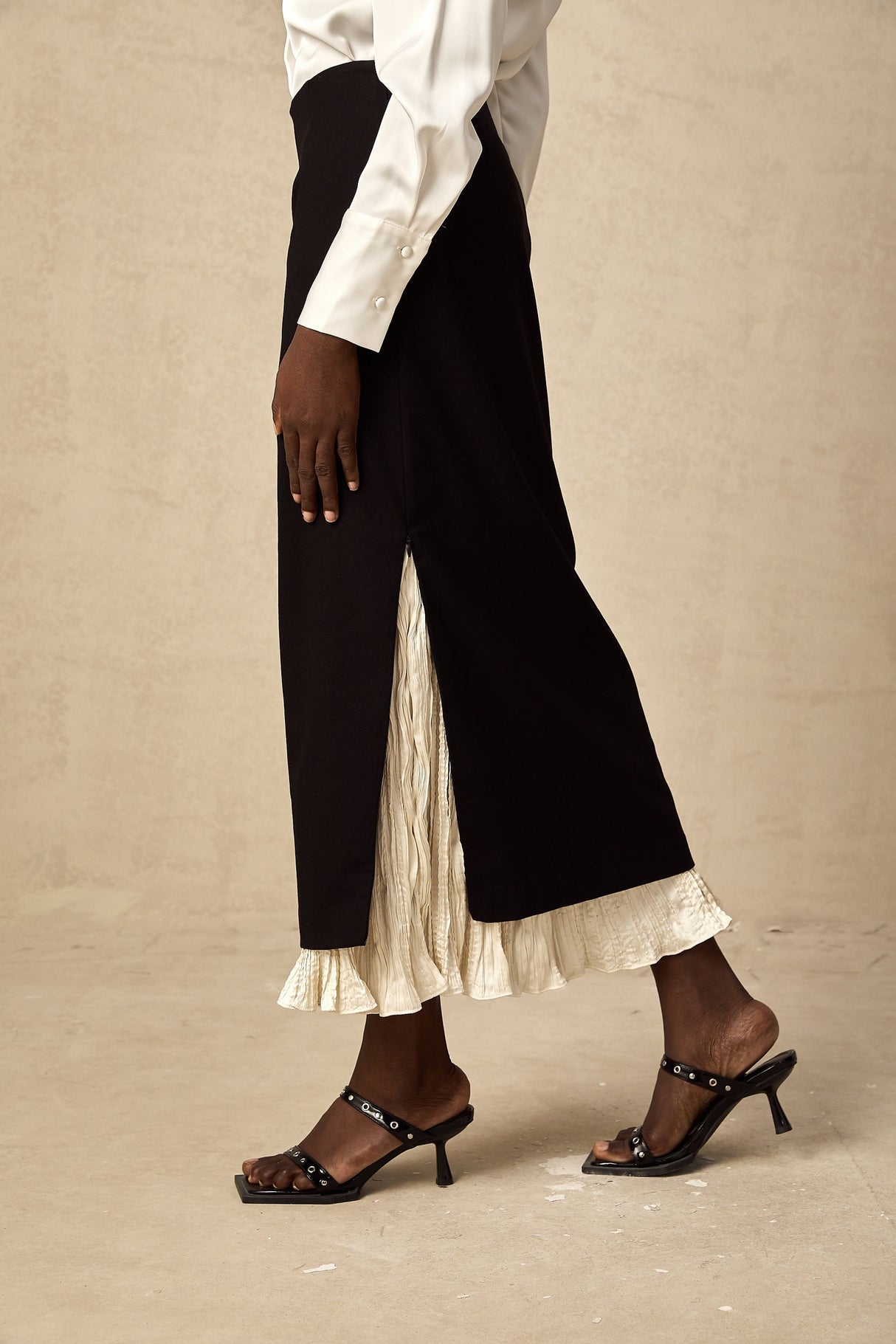 Woman wearing a midi length skirt with color blocked panels in contrasting shades standing against a plain background