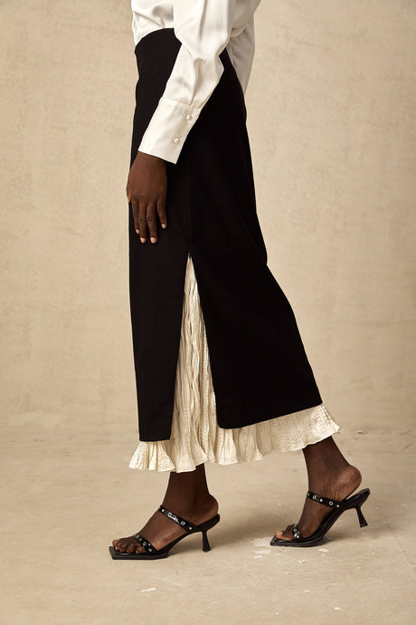 Woman wearing a midi length skirt with color blocked panels in contrasting shades standing against a plain background