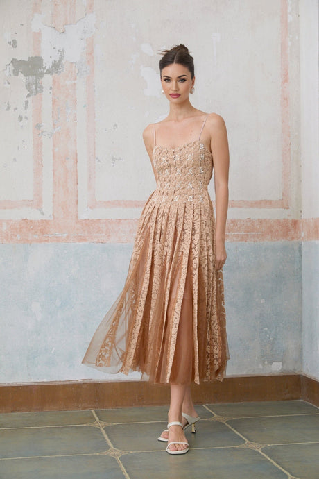Woman wearing a neutral colored crochet lace cardigan over a matching dress standing in a relaxed pose