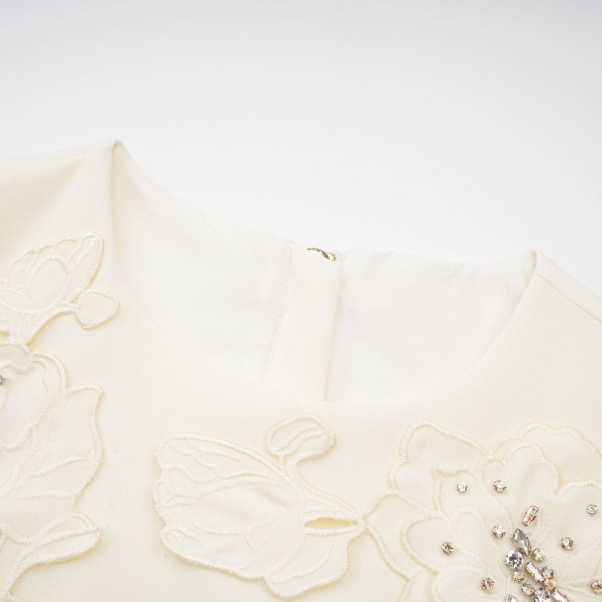 Woman wearing a neutral colored matching set consisting of a top and skirt with 3D petal details