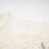 Woman wearing a neutral colored matching set consisting of a top and skirt with 3D petal details
