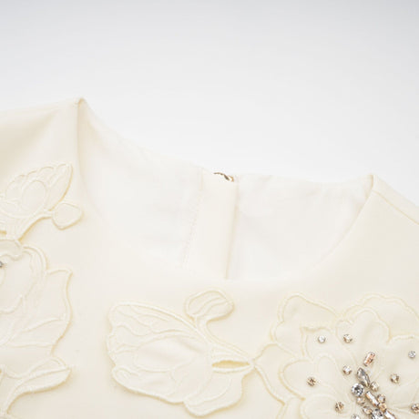 Woman wearing a neutral colored matching set consisting of a top and skirt with 3D petal details