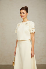 Woman wearing a neutral colored matching set with a 3D petal textured top and skirt named Coralie