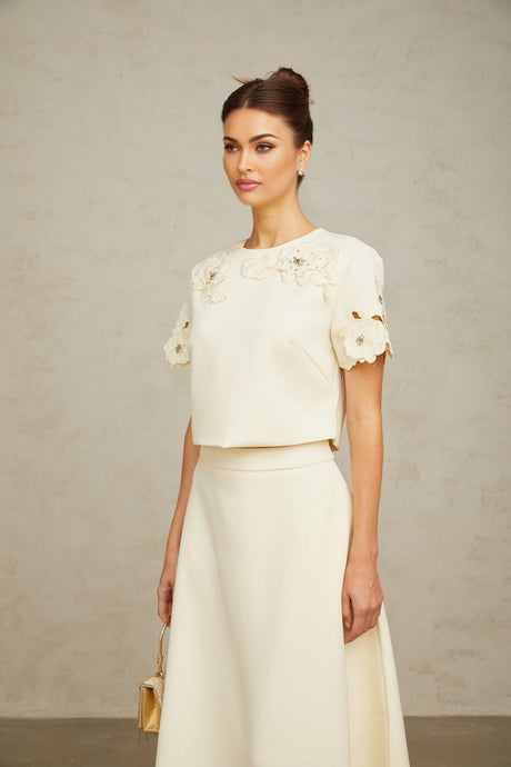 Woman wearing a neutral colored matching set with a 3D petal textured top and skirt named Coralie