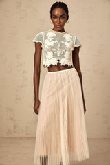 Woman wearing a neutral colored matching set with floral applique top and skirt