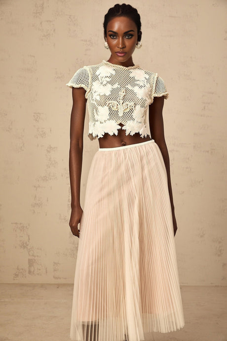 Woman wearing a neutral colored matching set with floral applique top and skirt