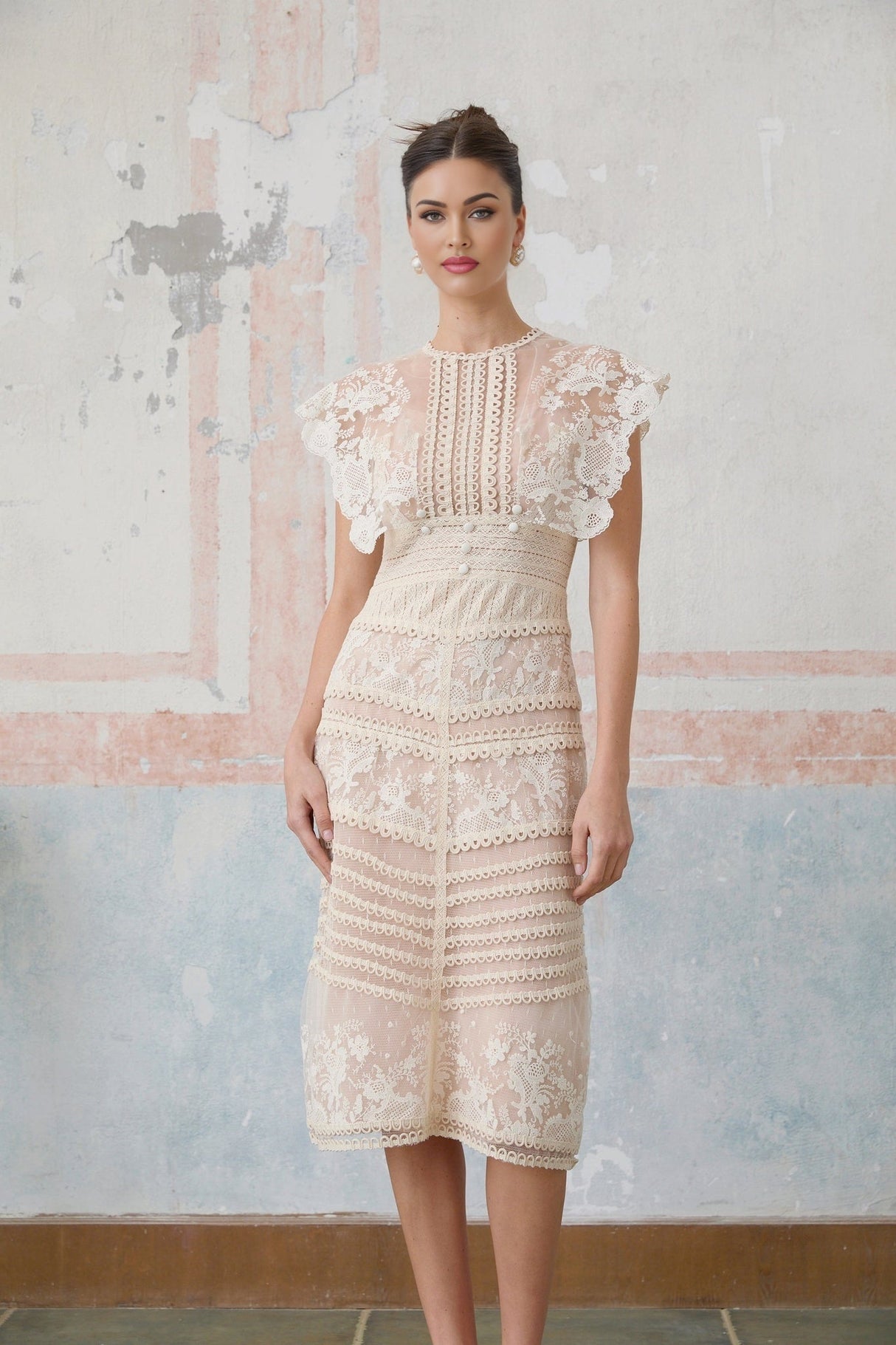 Woman wearing a neutral colored midi dress with floral embroidery and lace details