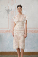 Woman wearing a neutral colored midi dress with floral embroidery and lace details
