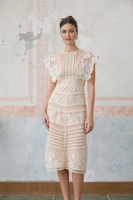 Woman wearing a neutral colored midi dress with floral embroidery and lace details