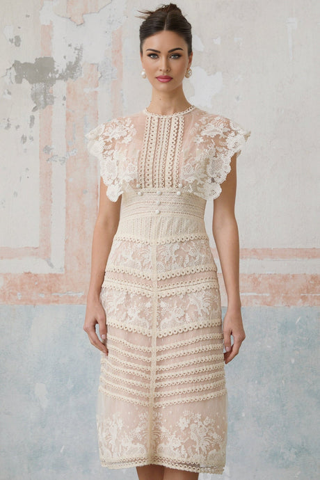 Woman wearing a neutral colored midi dress with floral embroidery and lace details