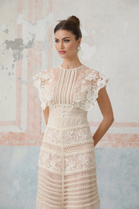 Woman wearing a neutral colored midi dress with floral embroidery and lace details