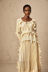 Woman wearing a neutral colored midi dress with gilded ruffles and a ruched bodice
