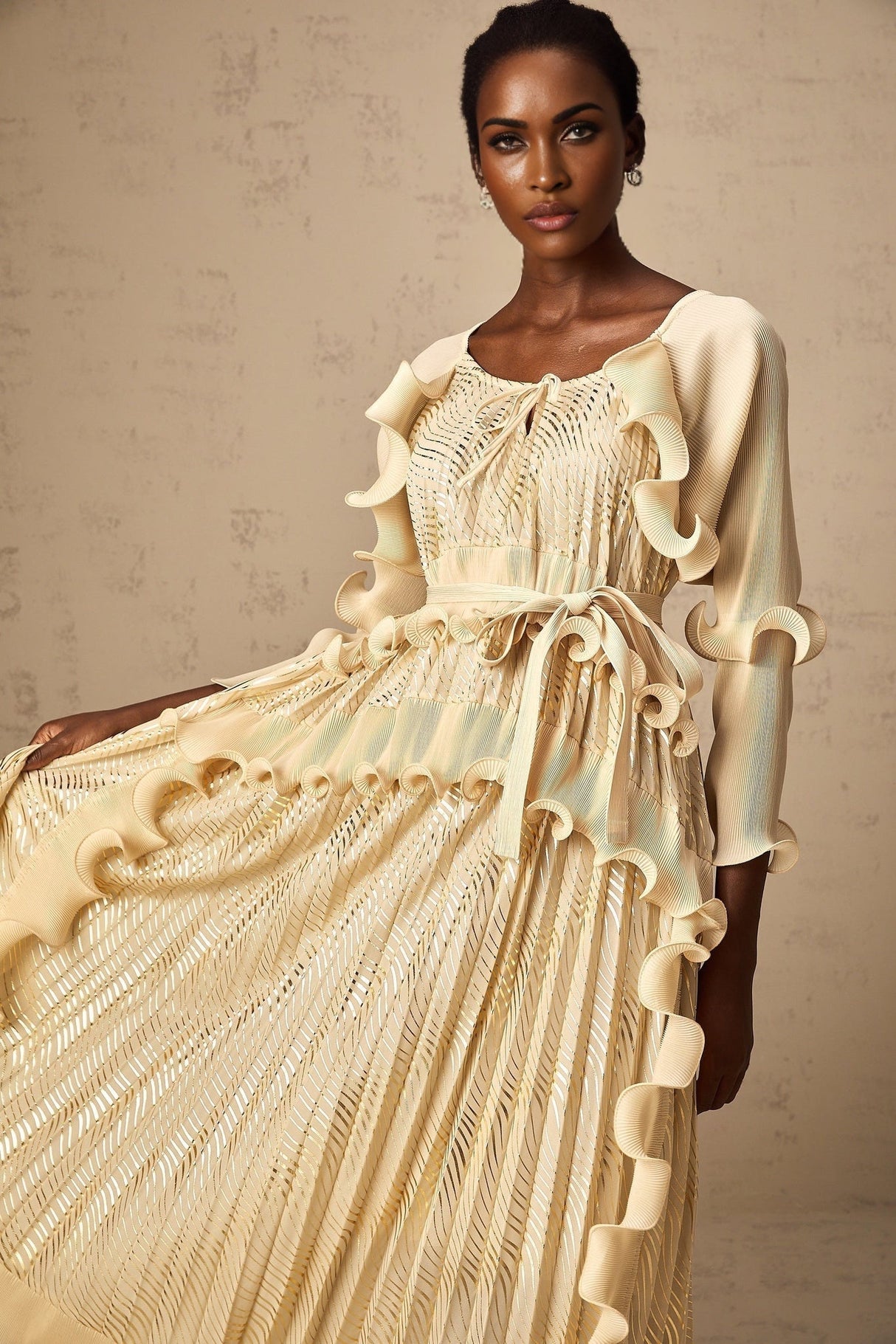 Woman wearing a neutral colored midi dress with gilded ruffles and ruffle details