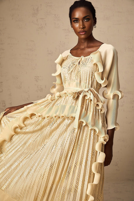Woman wearing a neutral colored midi dress with gilded ruffles and ruffle details