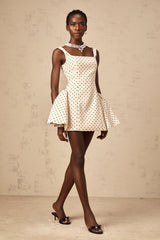 Woman wearing a neutral colored mini dress with polka dots and puff sleeves
