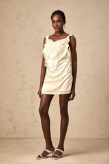 Woman wearing a neutralcolored mini dress with butterfly print and draped design