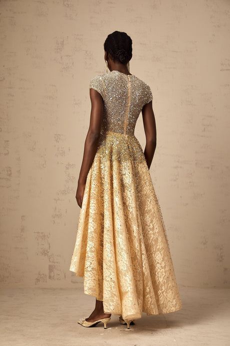 Woman wearing a neutralcolored sequined dress with a highlow hemline