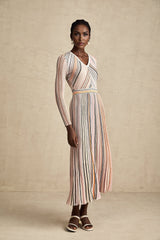 Woman wearing a pink metallic pleated midi dress with a flowing skirt and fitted bodice standing against a plain background