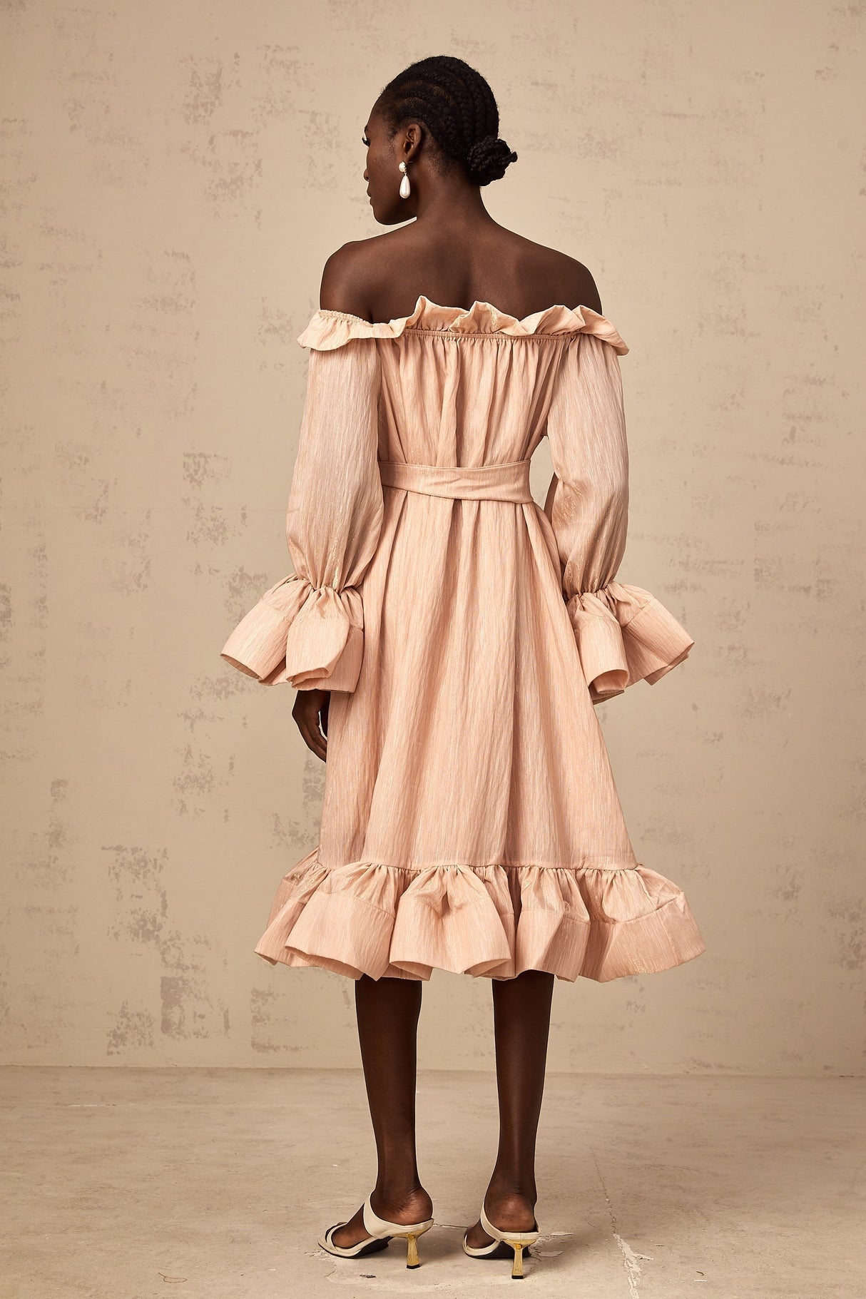 Woman wearing a pink midi dress with ruffled details and tied waist
