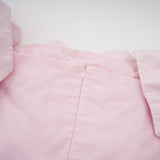 Woman wearing a pink offshoulder mini dress with 3D petal details The dress has a fitted silhouette and falls above the knee The model is shown standing against a plain background