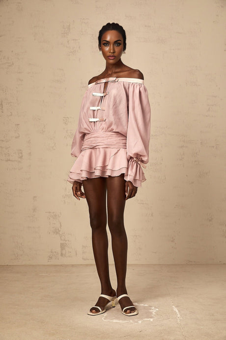 Woman wearing a pink offshoulder mini dress with a bow detail and ruffled hem