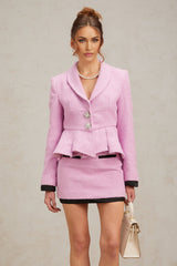 Woman wearing a pink tweed matching set consisting of a top and skirt with a textured fabric pattern