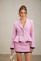 Woman wearing a pink tweed matching set with a top and skirt standing against a plain background