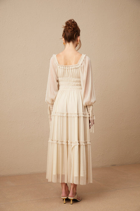 Woman wearing a pleated metallic midi dress with shirred detailing and a flowy silhouette named Camille